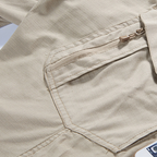 Close-up of beige pants with a pocket, showing the brand 'JIN EAGLE'.