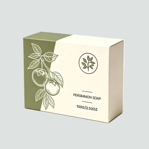A rectangular soap box for persimmon soap, shown with dimension lines indicating 85mm length, 60mm height, and 30mm width. The box is off-white and olive green with a line-art illustration of a persimmon branch on the front.